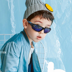 Child wearing sunglasses and a beanie with a yellow patch against a blue background