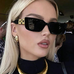 Close-up of a person wearing black sunglasses with gold accents, gold earrings, and a black turtleneck.
