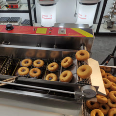 Donut-making machine with freshly made donuts in a kitchen setting